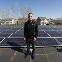 Todd Miller stands next to solar panels on the roof of his solar installation business in Ankeny, Iowa. (Charlie Neibergall/AP)