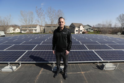 Todd Miller stands next to solar panels on the roof of his solar installation business in Ankeny, Iowa. (Charlie Neibergall/AP)
