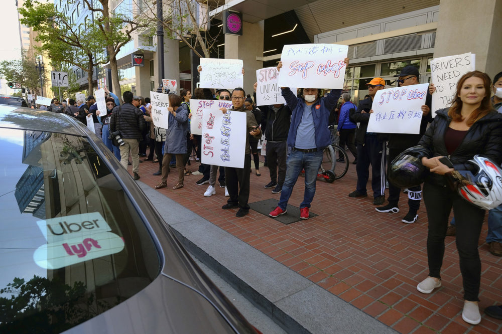 In this May 8, 2019,, file photo, Uber and Lyft drivers carry signs during a demonstration outside of Uber headquarters in San Francisco. Companies like Uber and Lyft helped create the so-called gig economy. (Eric Risberg, File/AP)