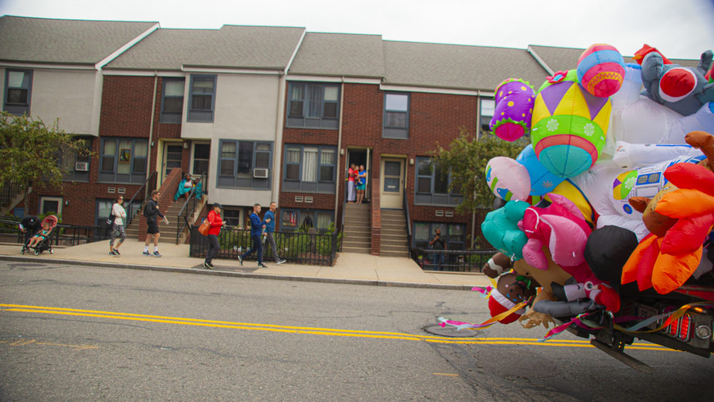 As the parade traveled through the city, the sounds of drums and horns call curious residents out of their homes. (OJ Slaughter for WBUR)