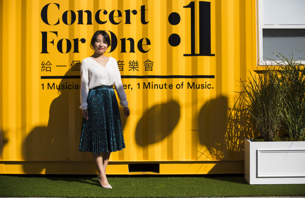 New England Conservatory graduate Rayna Yun Chou stands in front of shipping containers outfitted for her project, "Concert for One." (Erin Clark for WBUR)