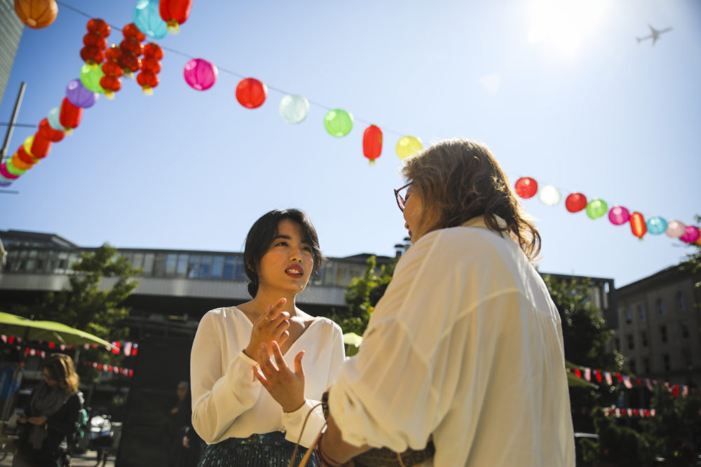 Rayna Yun Chou talks to a "Concert for One" guest in Chinatown. (Erin Clark for WBUR)