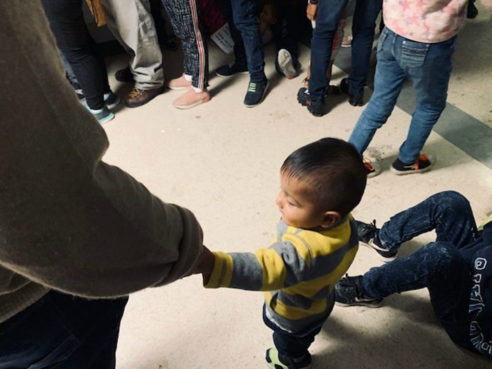 A little boy holds his father's hand at the Humanitarian Respite Center in McAllen, Texas. The father and son are from Honduras. (Courtesy)