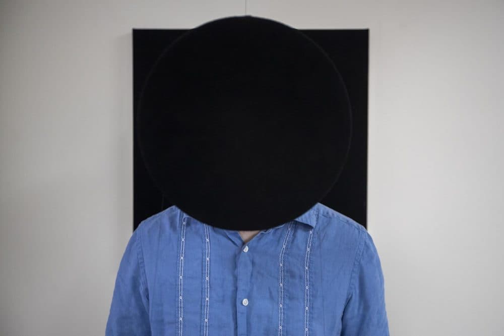 An interactive display called “The Vanishing Point.” A disc painted with the Singularity Black coating is suspended from the ceiling by wire is placed a few feet from the wall which has a board painted with the coating as well, creating a vanishing visual effect for anyone standing between the objects. (Jesse Costa/WBUR)