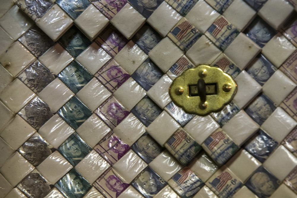 Detail of "Presidential Pardon," 1968, a purse made of woven cigarette packaging and stamps of U.S. presidents Washington, Jefferson, FDR, and Eisenhower. (Jesse Costa/WBUR)