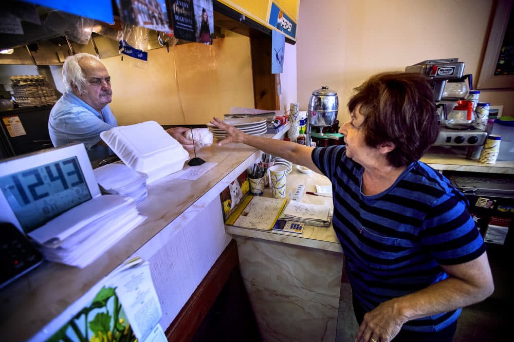 Charlie Kronopolous passes a sandwich to his wife Theodora for a customer at Charlie's Junction diner in Downtown Lynn. (Jesse Costa/WBUR)
