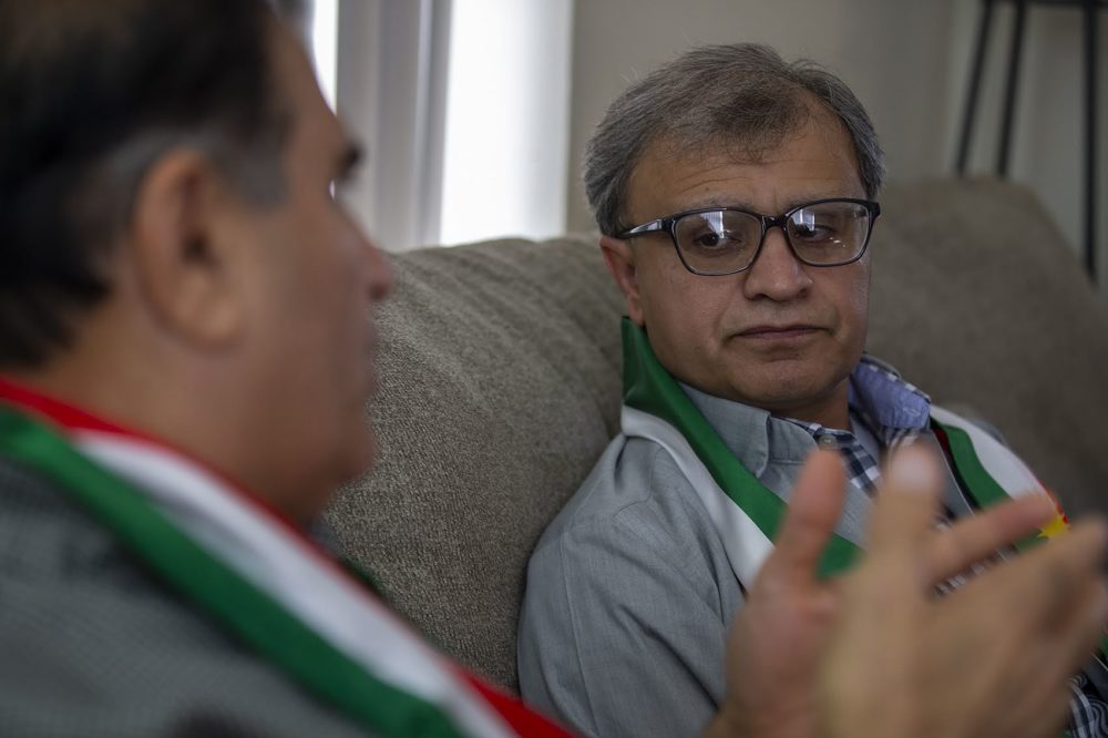 Delshad Osman listens to his father speak about his experience as a Peshmerga fighter in Iraq. (Jesse Costa/WBUR)