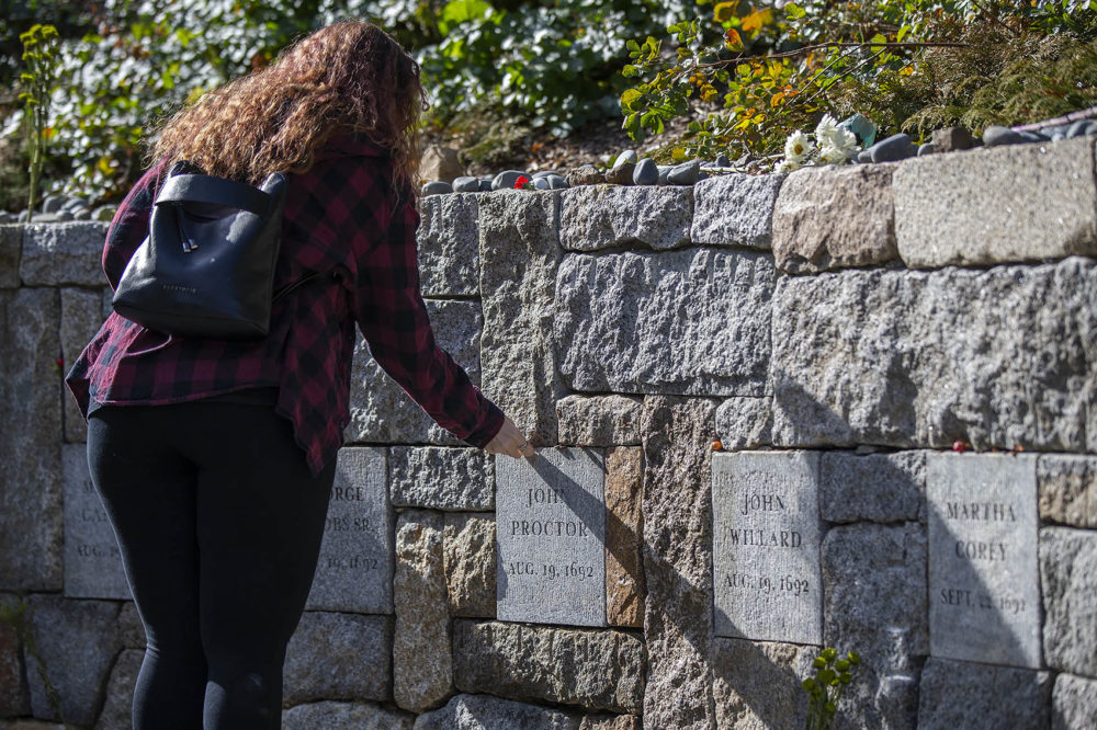 Brandi Mann traveled from Boaktown, New Brunswick, to leave a coin on the plaque of John Proctor, who was executed after defending his wife, Martha, who was accused of witchcraft. His plaque sits at Proctor's Ledge, where historians believe 19 people were wrongfully executed. (Jesse Costa/WBUR)