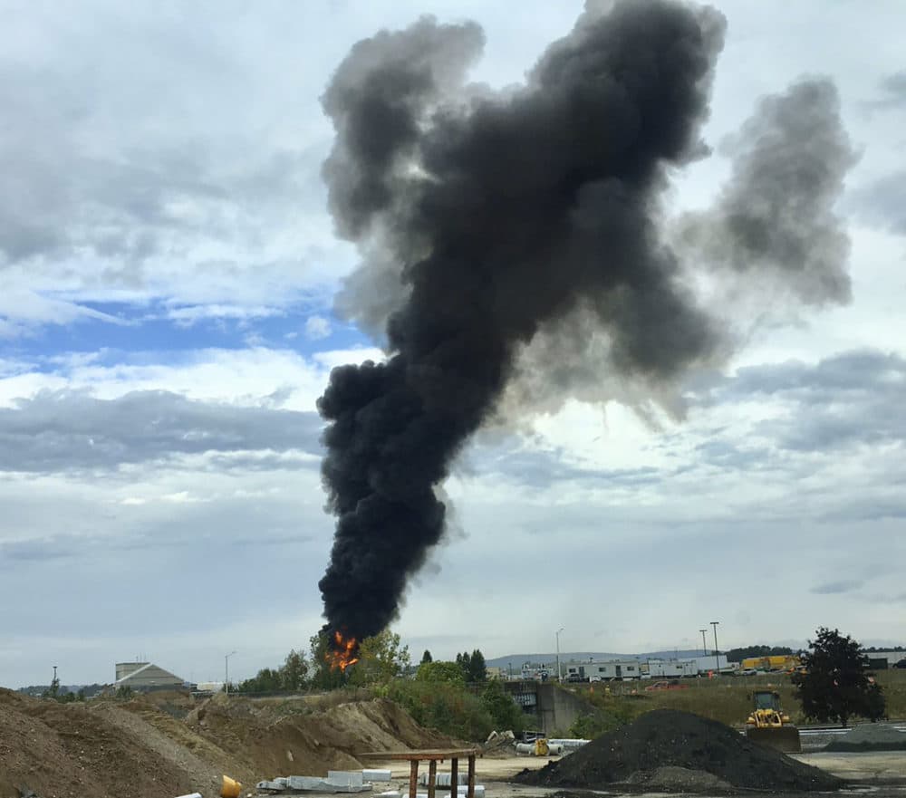 In this photo provided by Antonio Arreguin, smoke fills the sky after a World War II-era bomber plane crashed Wednesday outside Bradley International Airport north of Hartford. (Antonio Arreguin via AP)