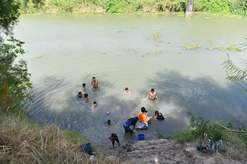 Camp residents washing in the murky waters of the Rio Grande. (Courtesy of Paul Goyette)