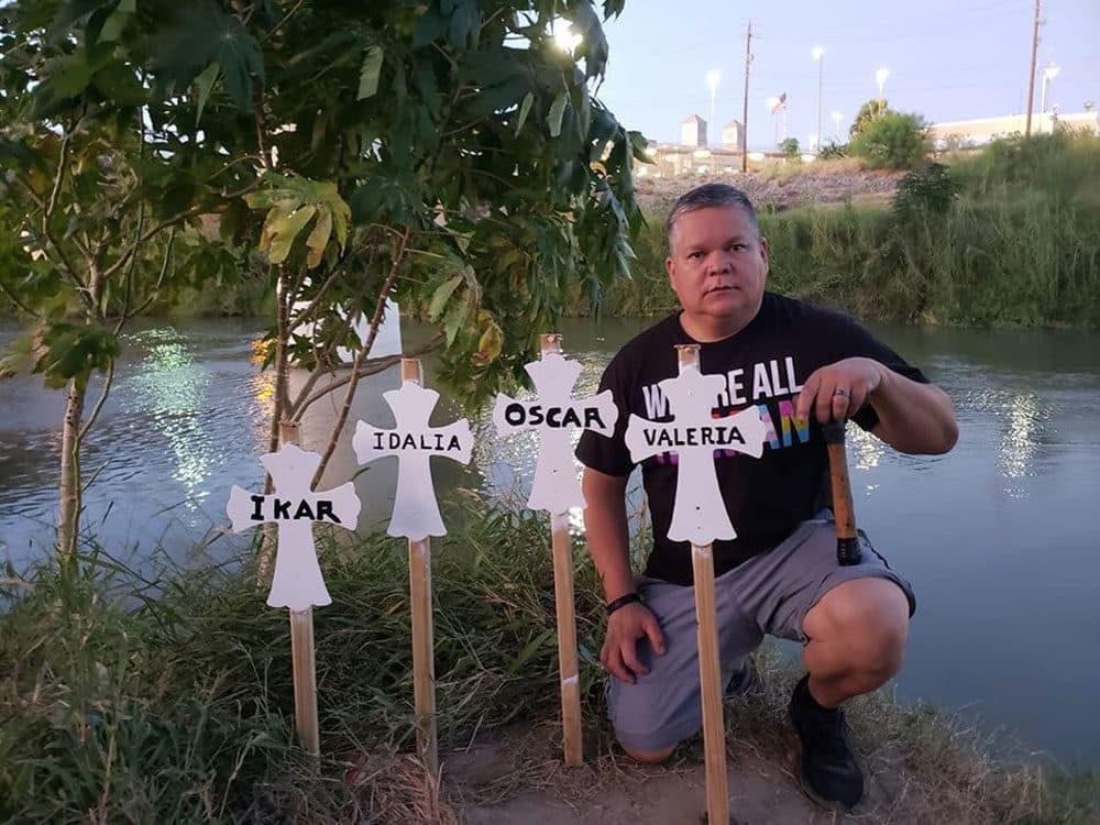 Mike Benavides kneels behind a makeshift grave for migrants who died while attempting to cross the Rio Grande (Courtesy of Ann Finch)