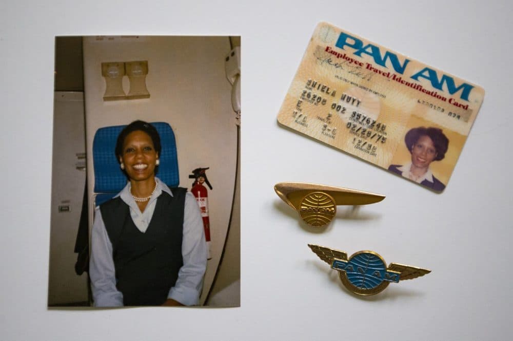 A photograph of Shelia Nutt on a Pan Am jet in 1985, her Pan Am identification card, and two Pan Am pins. (Jesse Costa/WBUR)
