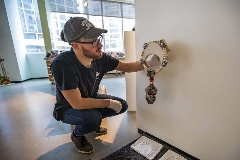 Curator Sam Aldrich sets to install a convertible neckpiece, "La Reine de Pèlerin" by Emiko Oye. (Jesse Costa/WBUR)