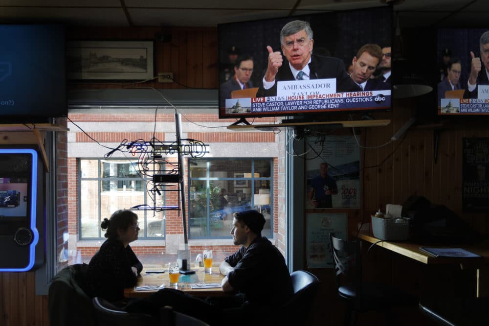 Olivia Tobin and her fiancé, Jordan Ashby, ignore the televised impeachment hearings playing on monitors at the Commercial Street Pub, Wednesday, Nov. 13, 2019, in Portland, Maine. (Robert F. Bukaty/AP)