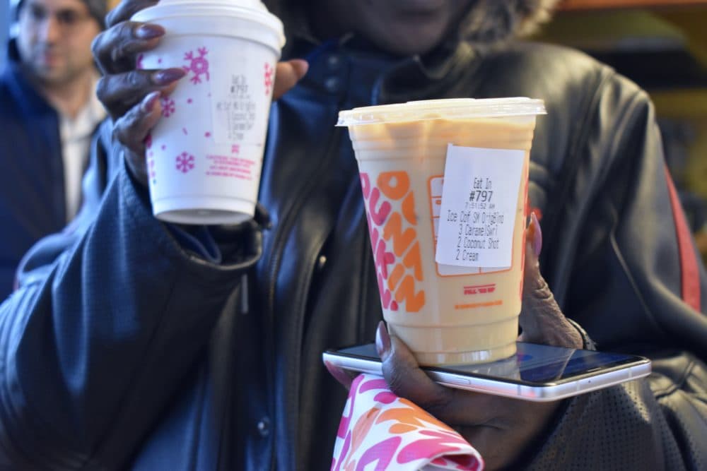 India Crawford displays her most recent order of a hot coffee and an iced coffee. (Meghan B. Kelly/WBUR)