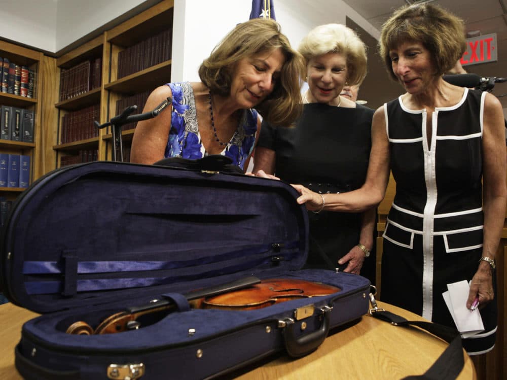 The Totenberg sisters — Amy (from left), Nina and Jill — see their father's stolen Stradivarius for the first time in 35 years at the U.S. attorney's office in New York City on Thursday. (Lydia Thompson/NPR)