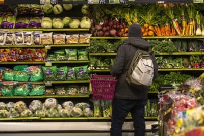 A customer peruses the produce at Roche Bros. in West Roxbury. (Jesse Costa/WBUR)