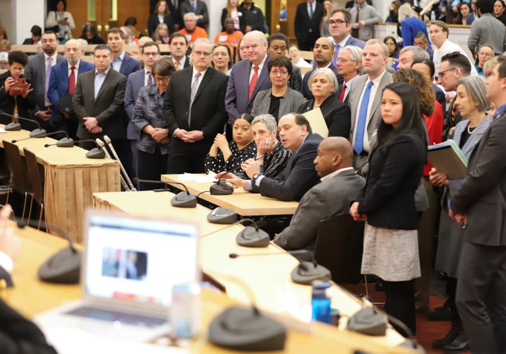 More than 20 lawmakers, led by Rep. Liz Miranda, Rep. Ruth Balser, and Sen. Jamie Eldridge (at microphone), crowded around a hearing table to voice support for limits on immigration enforcement cooperation between local and federal officials. (Photo: Sam Doran/SHNS)
