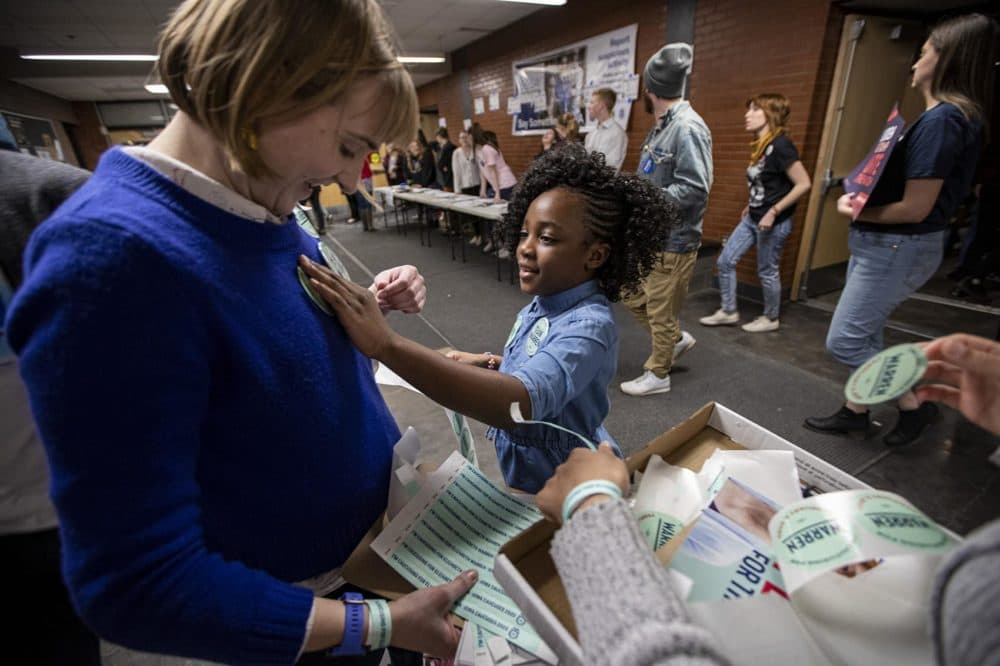 7-year-old Titi Inene places an Elizabeth Warren sticker on a supporter before she enters the auditorium at Central Campus High School in Des Moines. (Jesse Costa/WBUR)