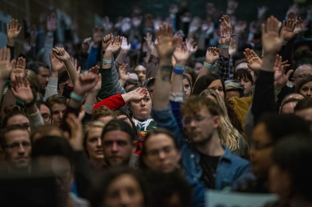 Caucus participant at Central Campus High School raise their hands to be counted. (Jesse Costa/WBUR)