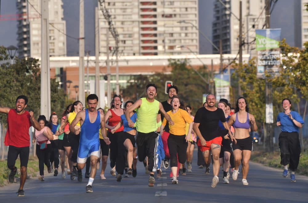 Dancers run down a street in Santiago's San Joaquín neighborhood during a performance of "Emerger" by choreographer José Vidal. (Jorge Sanchez for WBUR)