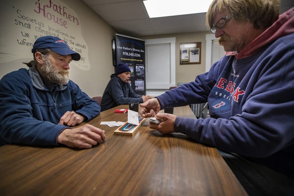Two guests at Our Father's House play a hand of cribbage while they wait for dinner to be served. (Jesse Costa/WBUR)