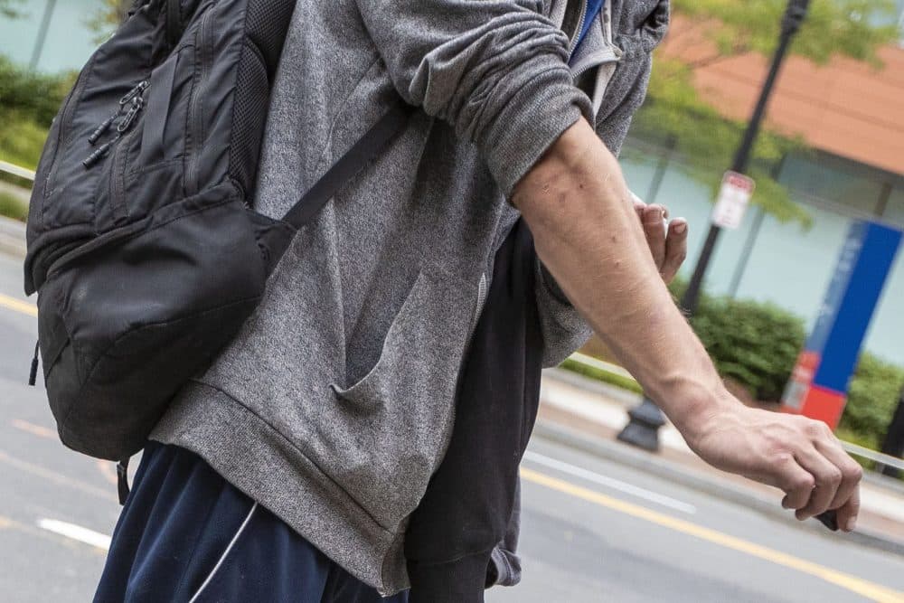 A young man injects drugs on a street in the South End. (Jesse Costa/WBUR)