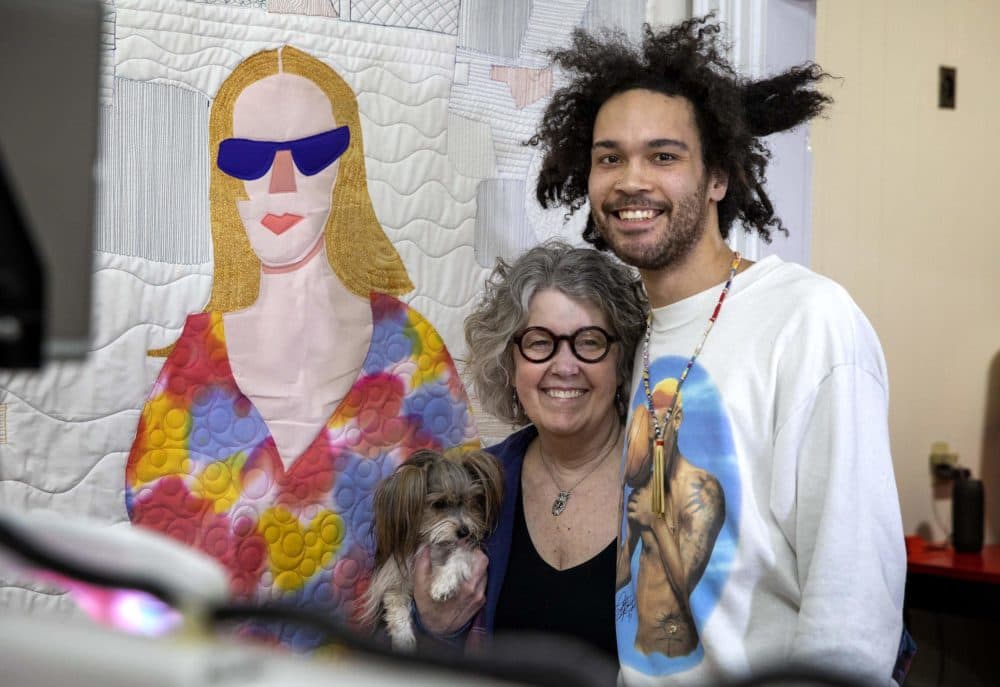 Michael Thorpe, his mother Susan Richards and their dog Gracie, stand next to a quilt portrait Michael's partner Cecilia Gehred. (Robin Lubbock/WBUR)