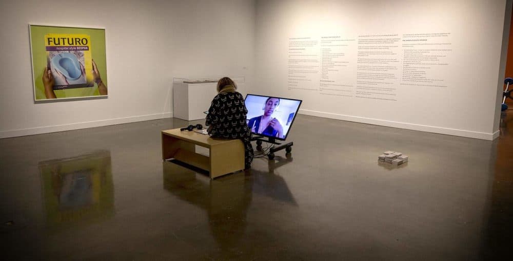 A visitor sits in the first room of MIT's exhibit "Colored People Time: Mundane Futures, Quotidian Pasts, Banal Presents" at the List Visual Arts Center. (Robin Lubbock/WBUR)