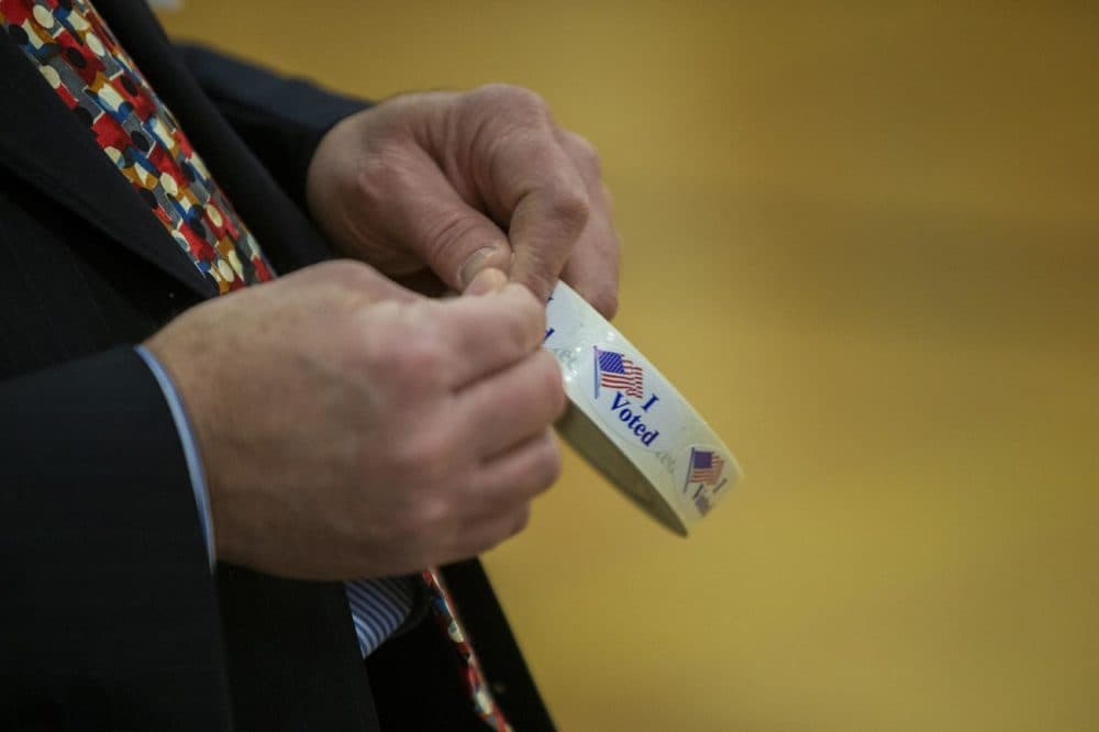 William Tucker passes out “I Voted” stickers after people finish voting at Portsmouth Middle School. (Jesse Costa/WBUR)