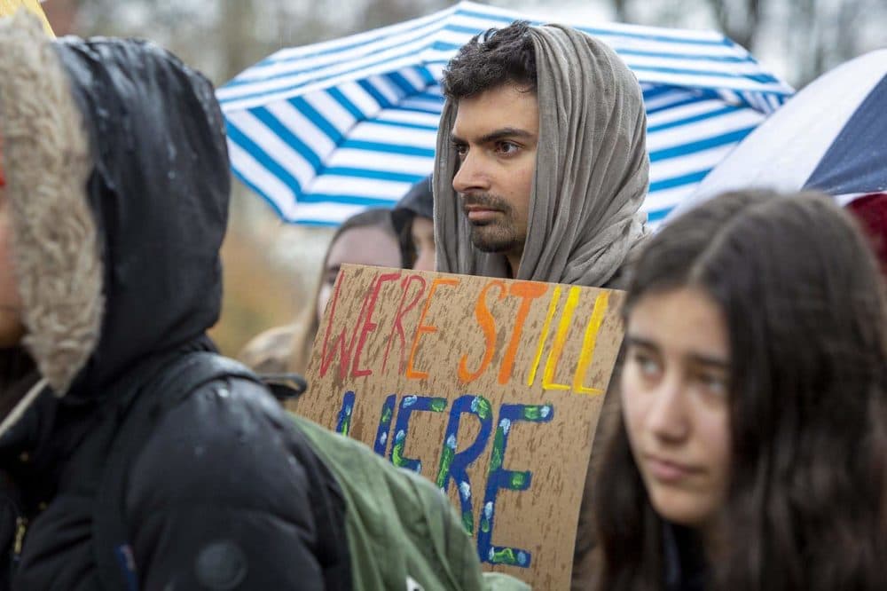 Ph.D student Aneil Tripathy holds up a banner at a Brandeis demonstration. (Robin Lubbock/WBUR)