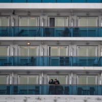 Passengers wearing face masks look out from their cabin on the Diamond Princess cruise ship in quarantine due to fears of COVID-19. (Philip Fong/AFP/Getty Images)