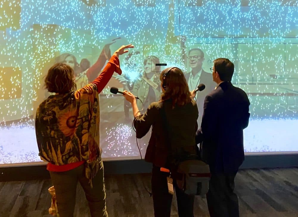 Host Tiziana Dearing, Producer Zoë Mitchell, and Museum Of Science President Tim Ritchie stand in front of the particle mirror at the Museum of Science. (Courtesy: Museum of Science)