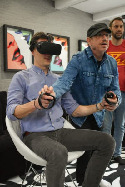 Scott Matalon le muestra al anfitrión Peter O'Dowd cómo operar controladores de realidad virtual de mano.  (Allison Hagan / Aquí y ahora)