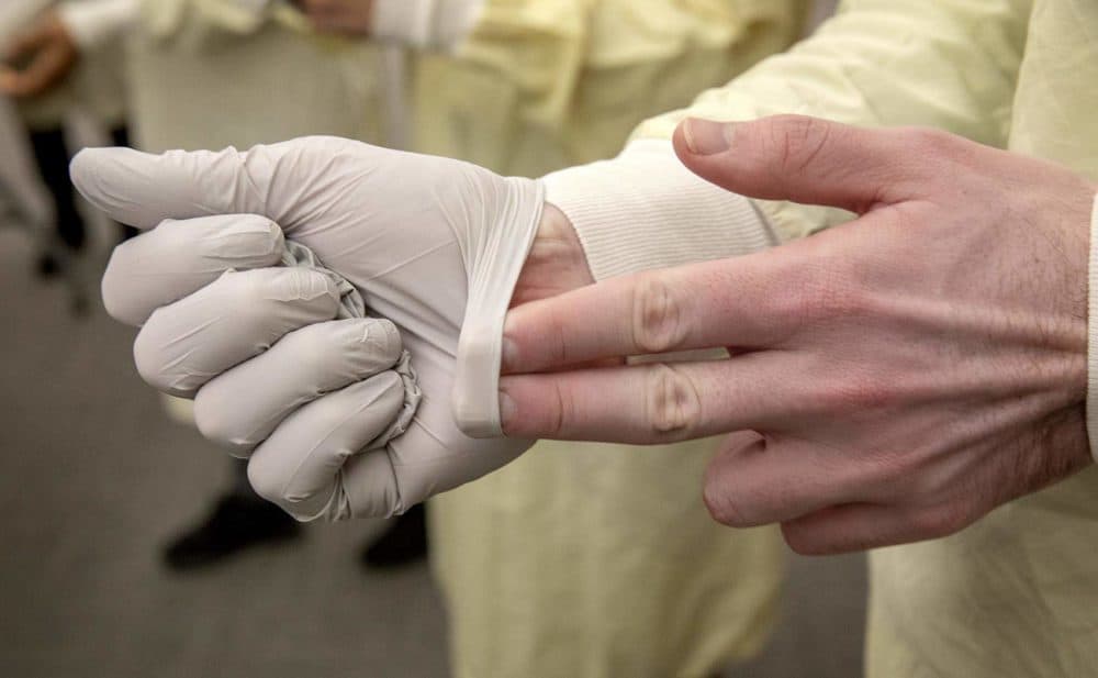 A member of Tufts medical staff removes protective gloves without touching their exterior surface. (Robin Lubbock/WBUR)