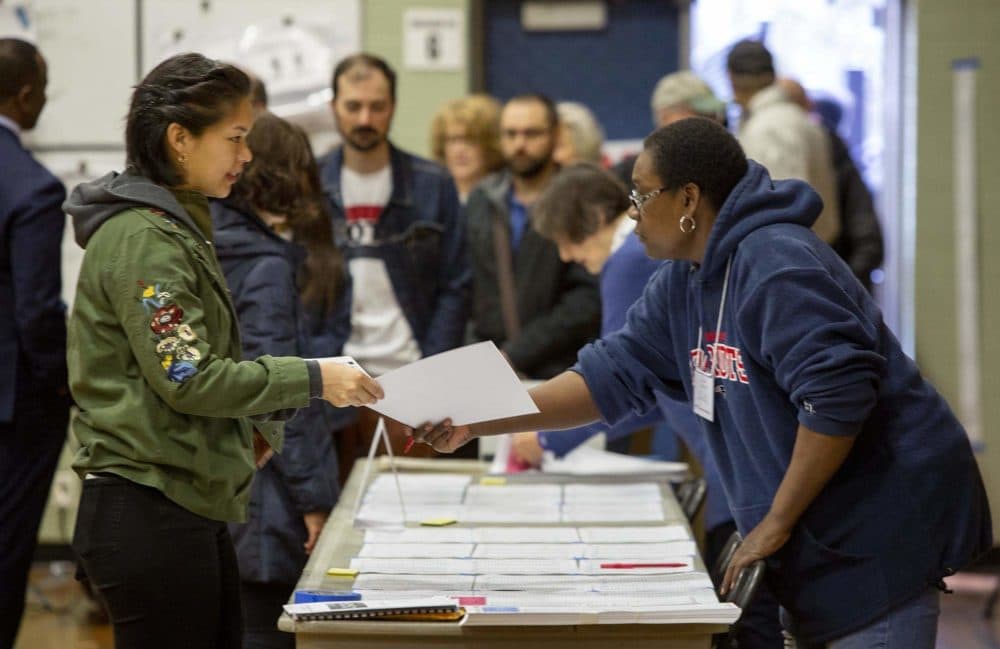 A voter receives a ballot at Graham and Parks School in Cambridge, as primary elections get under way in Massachusetts. (Robin Lubbock/WBUR)