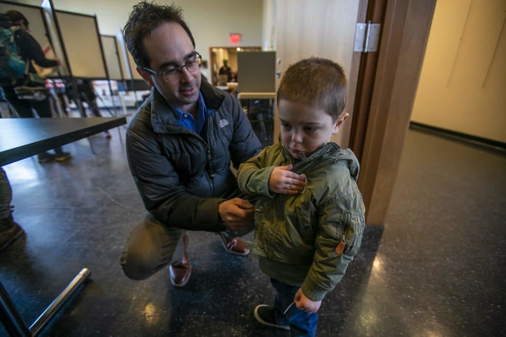 Two-year-old Avery Albert places an 'I voted' sticker on his jacket after he assisted his father, Chris, with voting Tuesday at the Allston branch of the Boston Public Library. (Jesse Costa/WBUR)