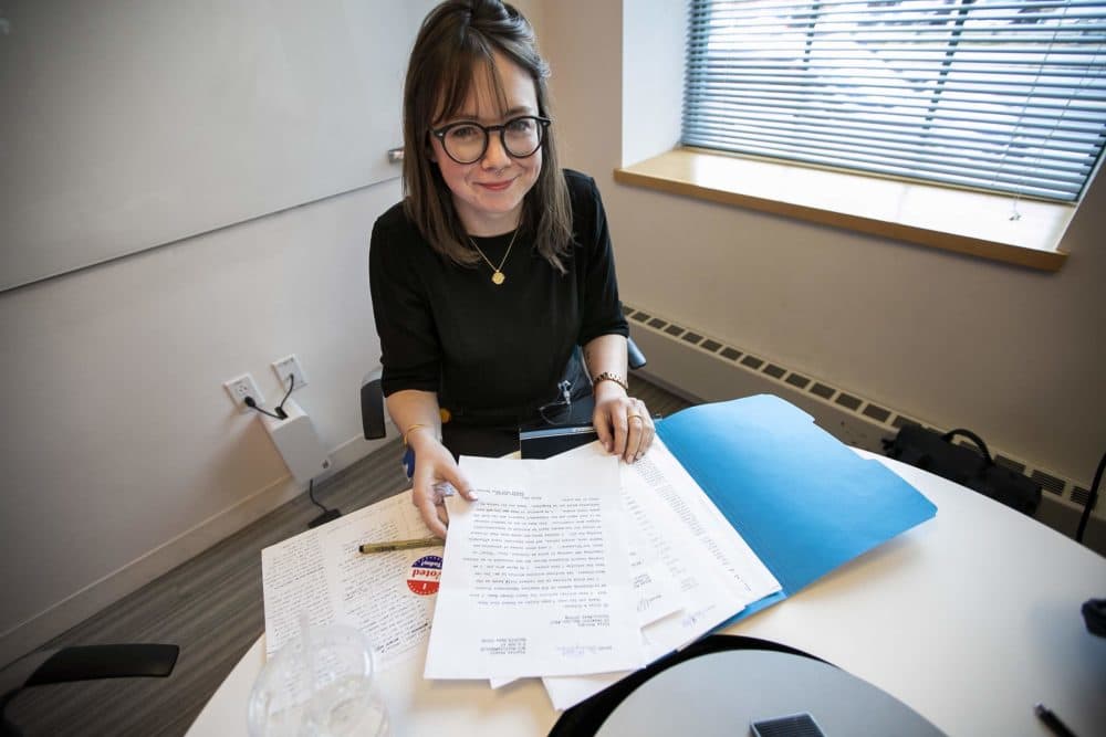 Eliza Mulcahy opens a folder with letters to her pen pal in prison, whose preferred candidate is Bernie Sanders. (Jesse Costa/WBUR)