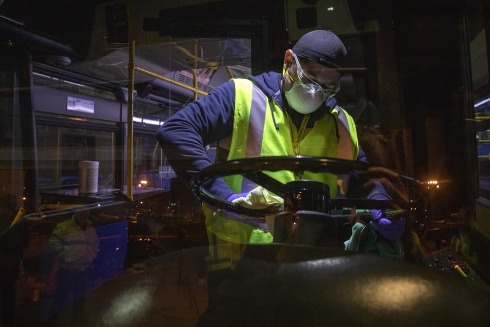 The MBTA’s Fradwin Suarez wipes down the steering wheel of the bus overnight at the Charlestown bus garage. (Robin Lubbock/WBUR)