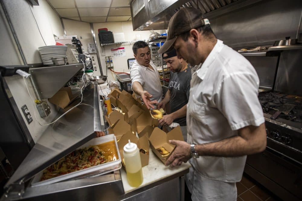 The kitchen staff at Trina’s Starlite Lounge in Somerville assembling hamburgers and cheeseburgers for takeout Monday. (Jesse Costa/WBUR)