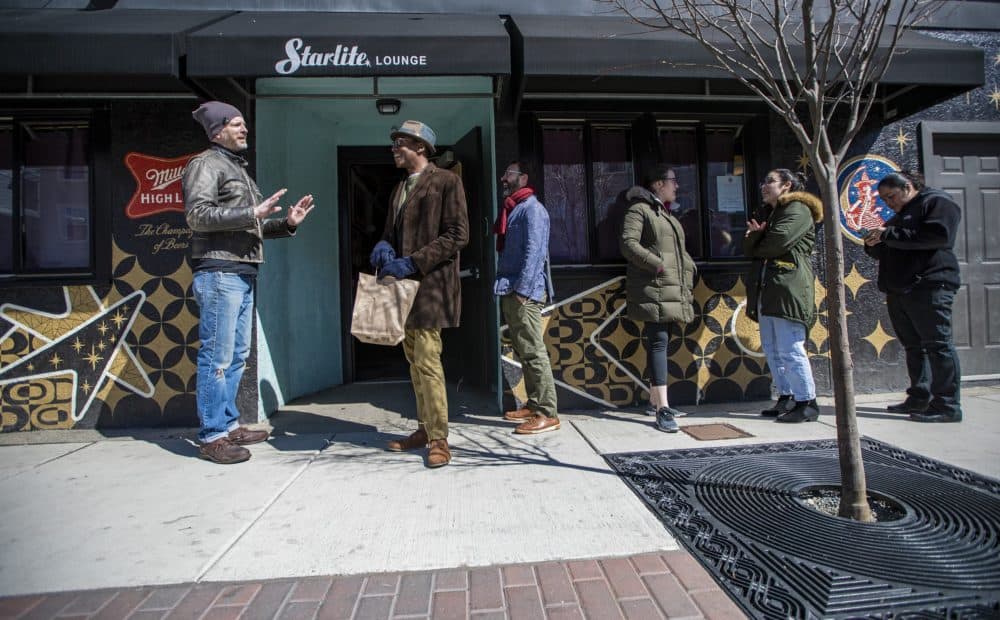 Trina’s Starlite Lounge co-owner Josh Childs stands outside to organize the line of patrons forming outside to pick up food. (Jesse Costa/WBUR)