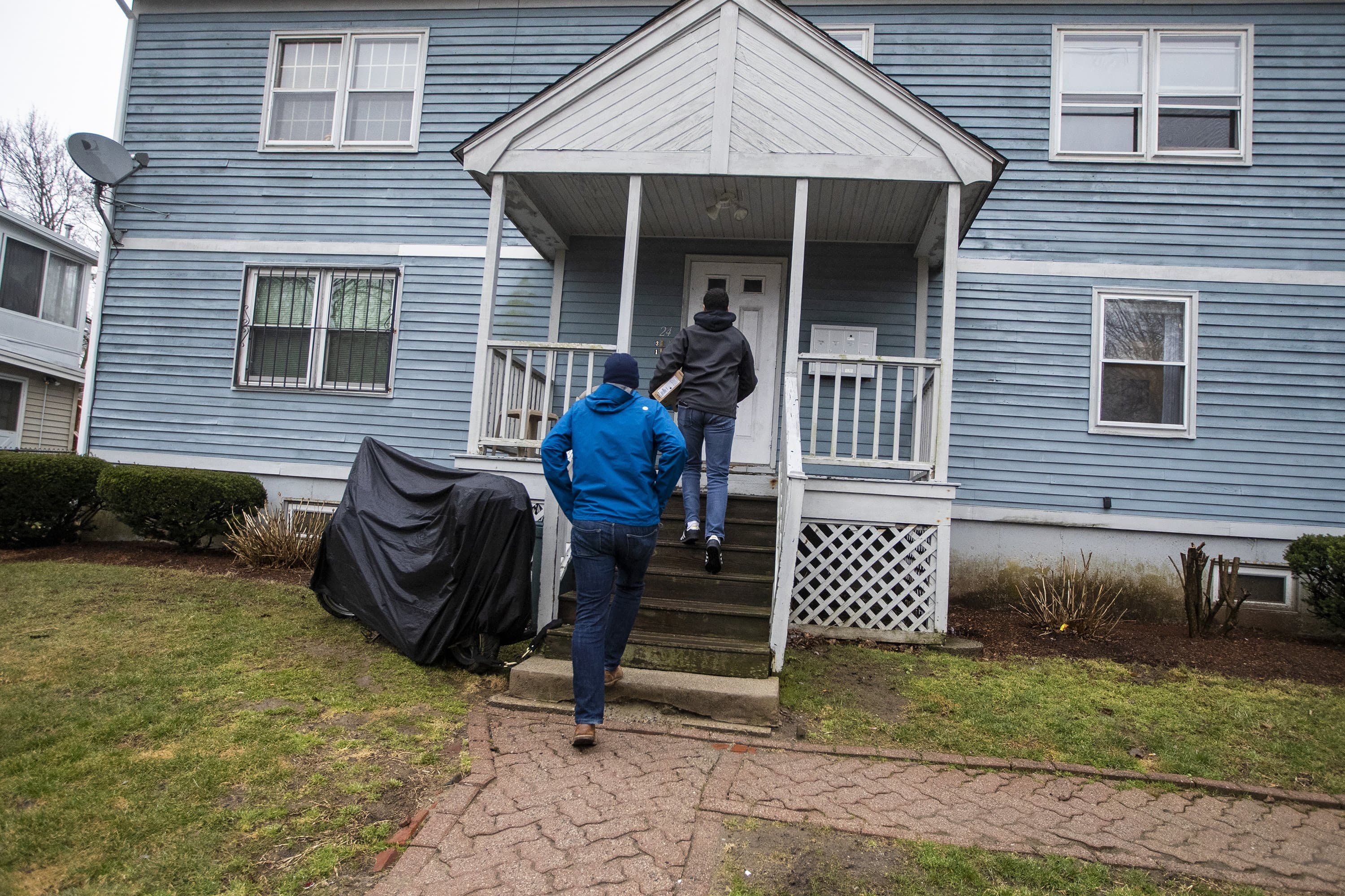 Mark Racine, Director of Development at BPS, and Giscar Centeio deliver a Chromebook to a students house in Roxbury. (Jesse Costa/WBUR)