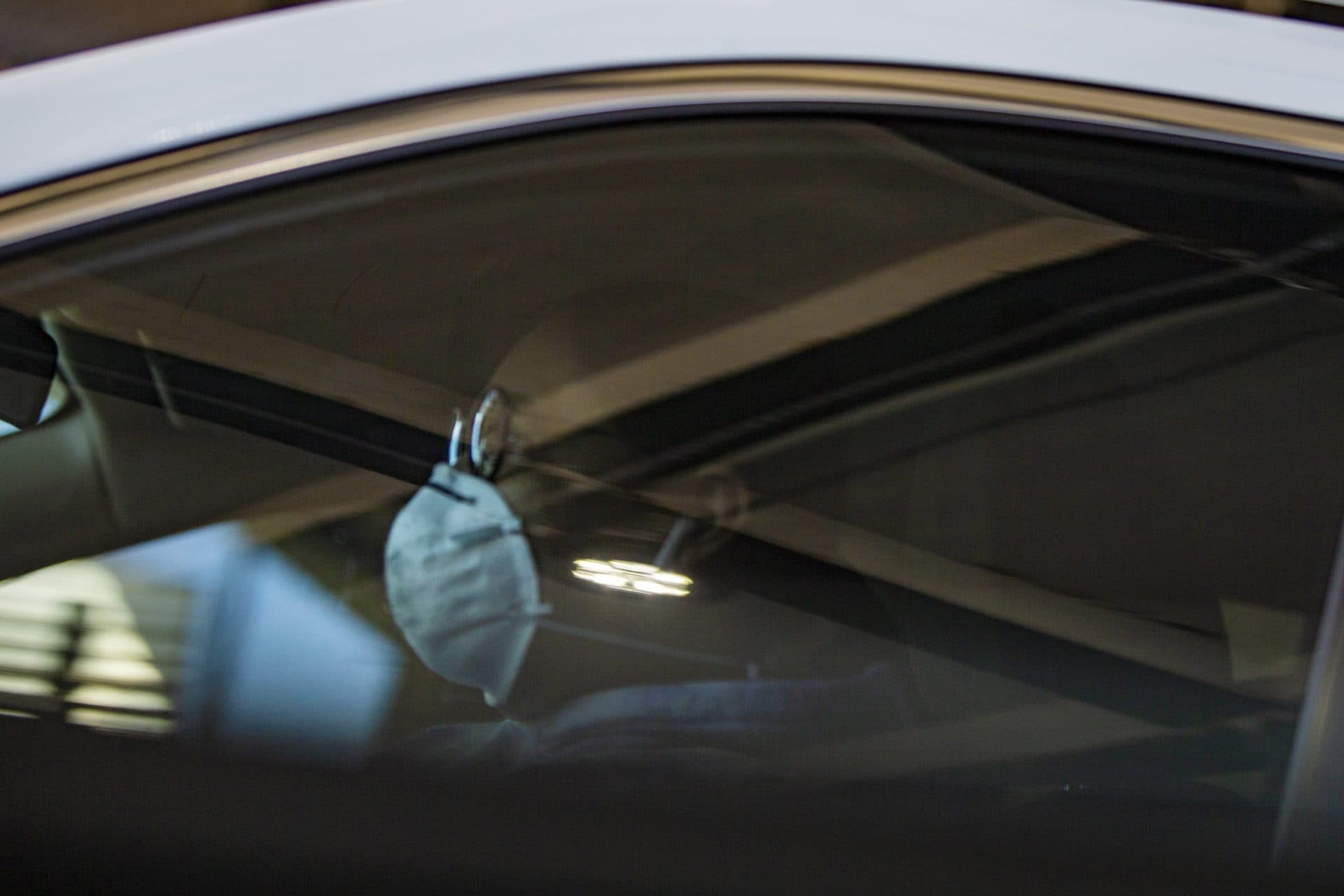 A woman wearing a mask driving a car stopped at a signal light on Cambridge Sreet in Boston. (Jesse Costa/WBUR)