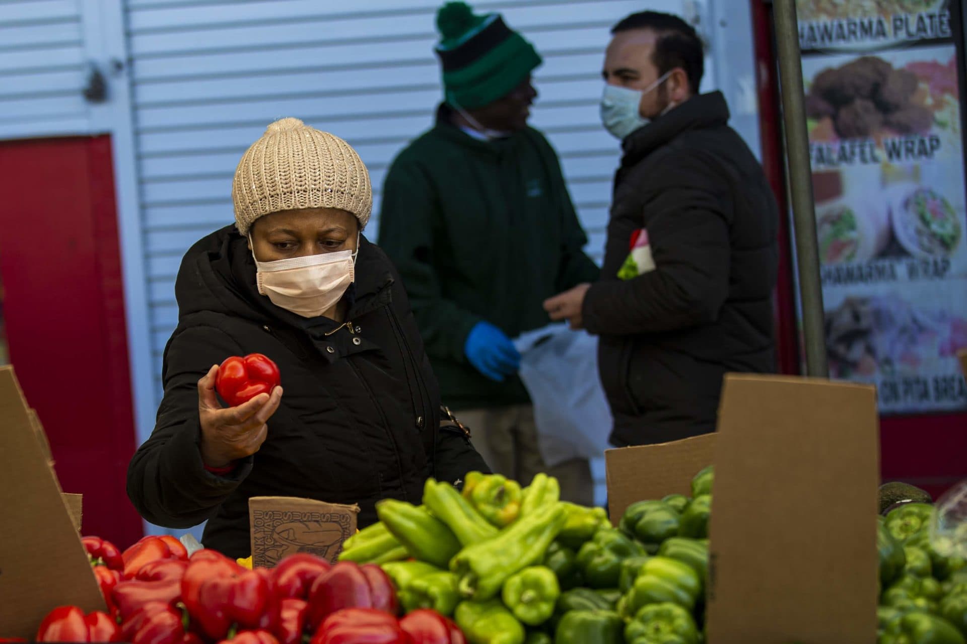 A woman picks up and inspects a pepper at Haymarket on Blackstone Street. (Jesse Costa/WBUR)