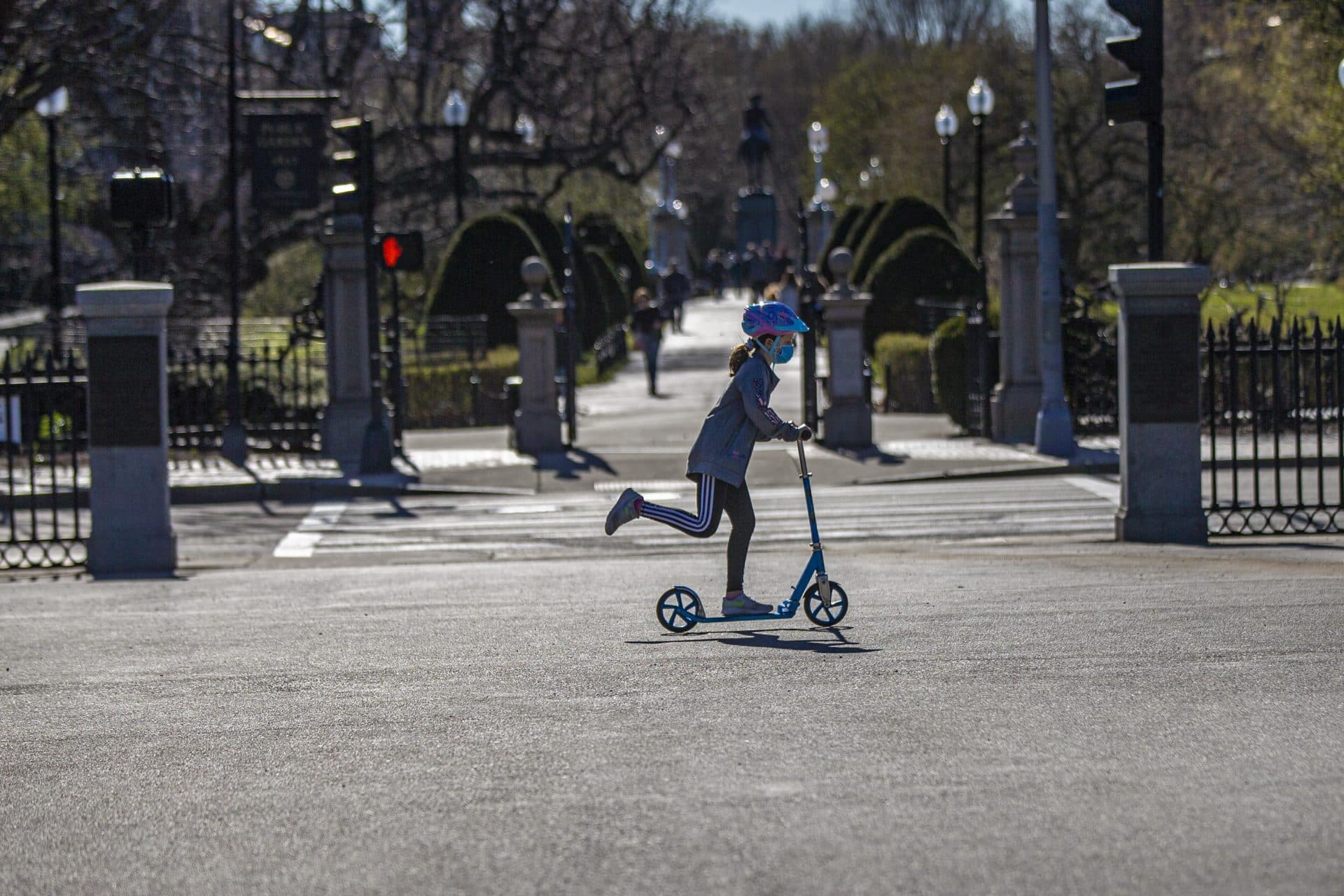 A young girl rides her scooter in Boston Common along Charles Street. (Jesse Costa/WBUR)