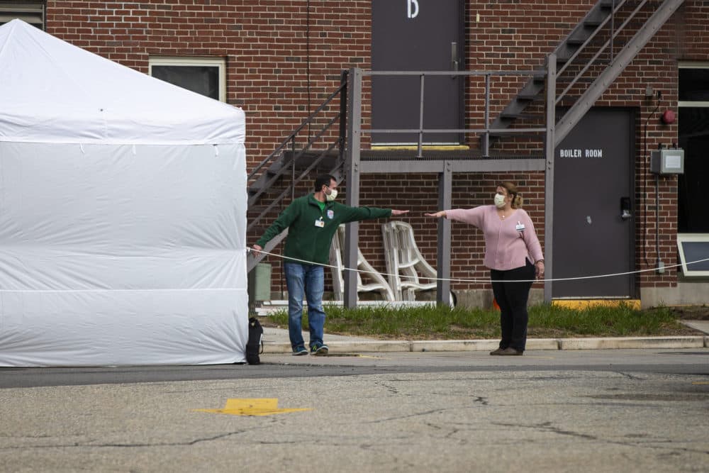 Two workers at the Soldiers’ Home in Holyoke reach out to one another, but do not touch, to say goodbye. (Jesse Costa/WBUR)