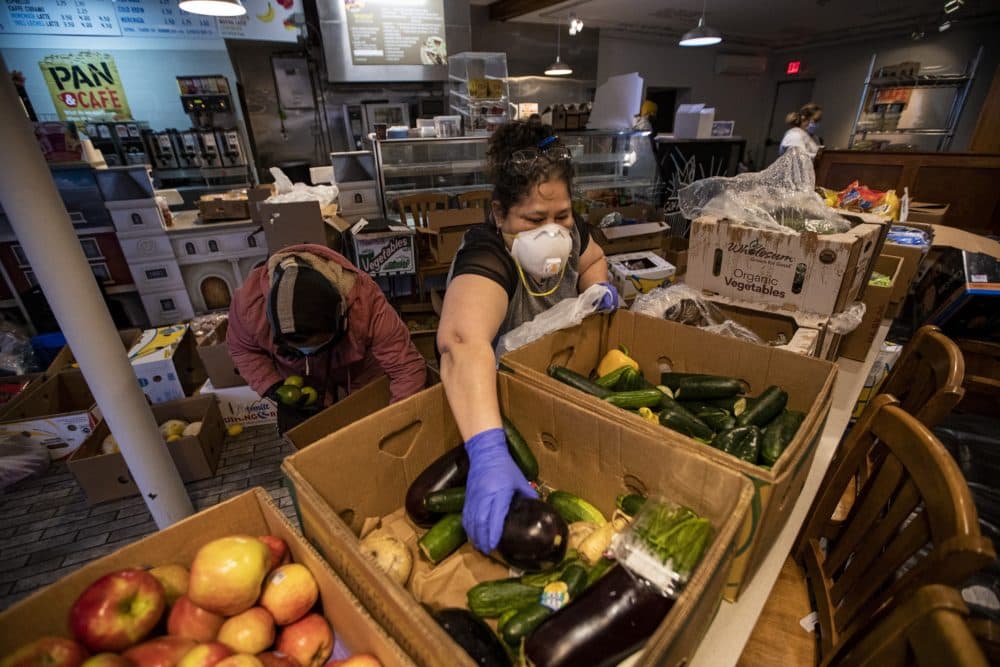 A volunteer from the Chelsea Collaborative picks up an eggplant to be placed into orders for local residents to pick up at the Pan Y Cafe in Carey Sq. (Jesse Costa/WBUR)