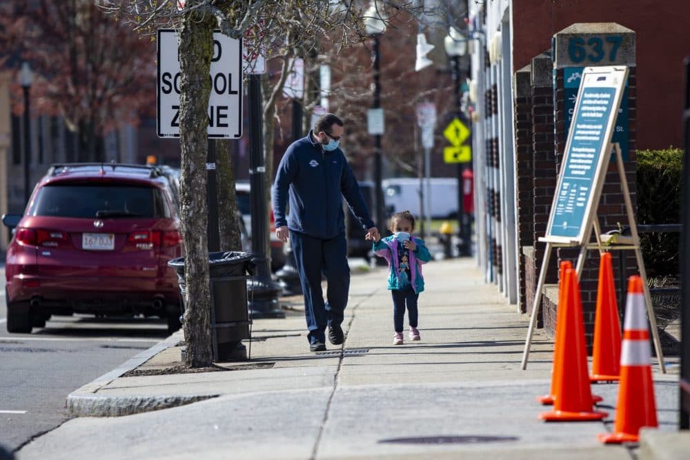 A father and his young daughter walk down Washington Street on their way to Codman Square Health Center. (Jesse Costa/WBUR)