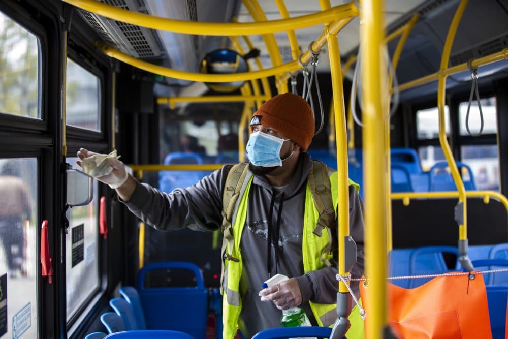 Marino Diaz Cruz wipes down the surfaces inside an MBTA bus with disinfectant after it pulled into Ashmont Station From Jackson Square. (Jesse Costa/WBUR)