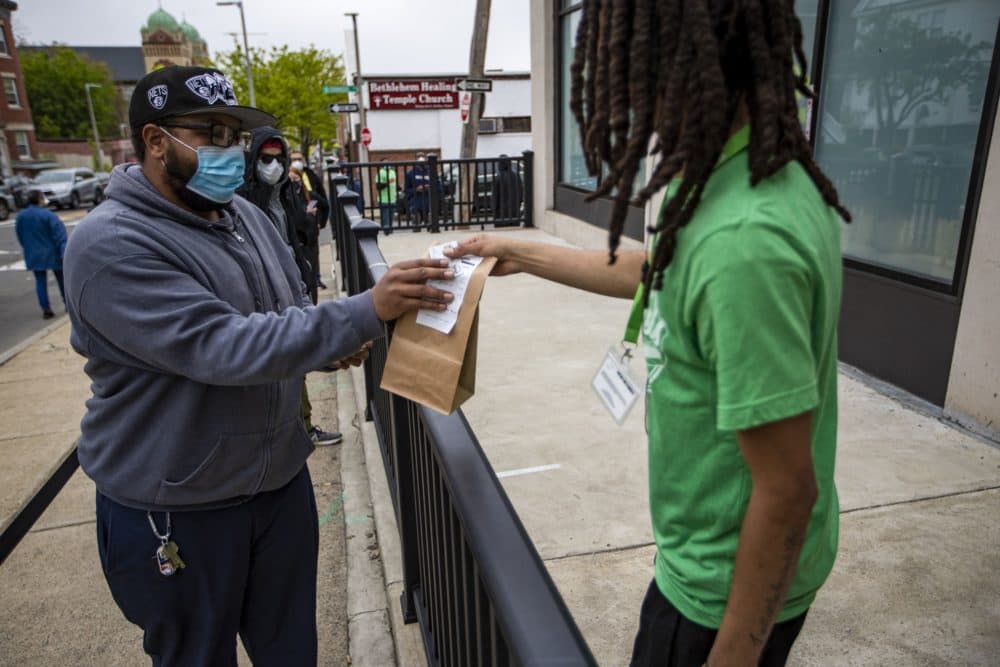 A worker from Pure Oasis brings out an order to a customer on the first day of reopening. (Jesse Costa/WBUR)